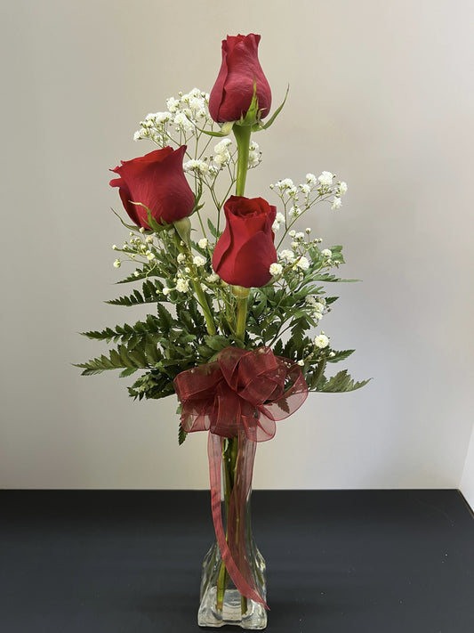 Three red roses in a bud vase